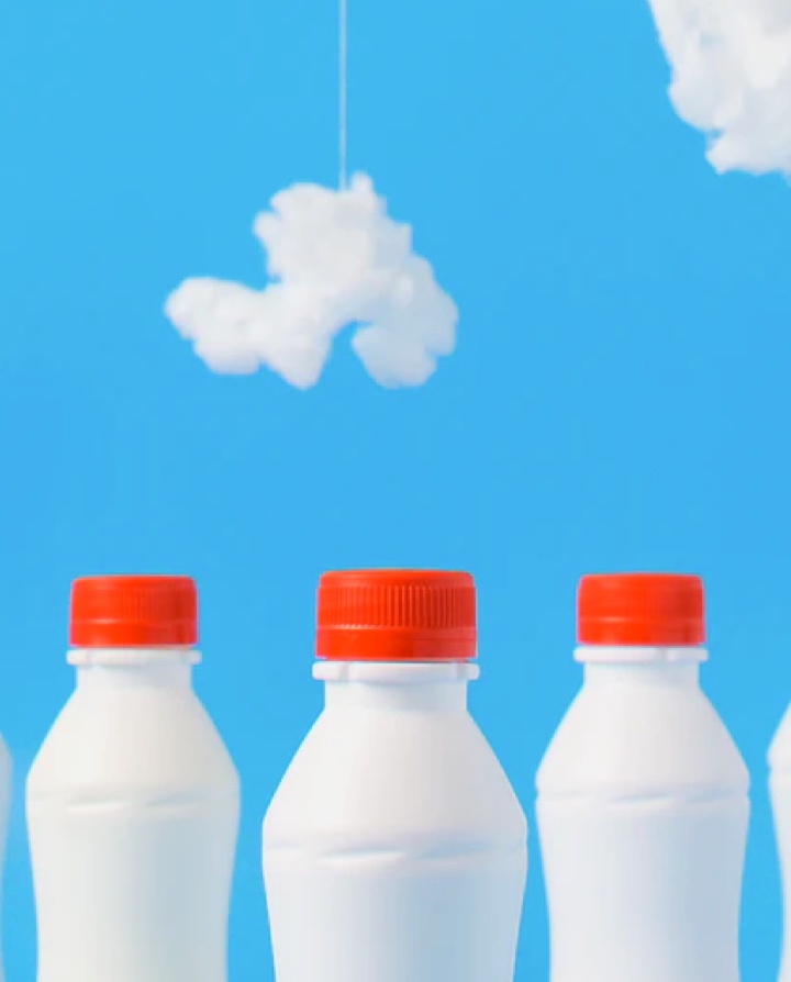 three bottles of milk with blue background and clouds
               