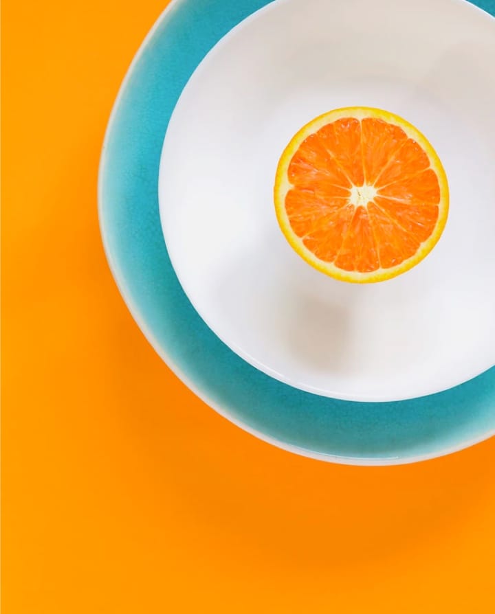 sliced ​​orange on top of plate and orange background